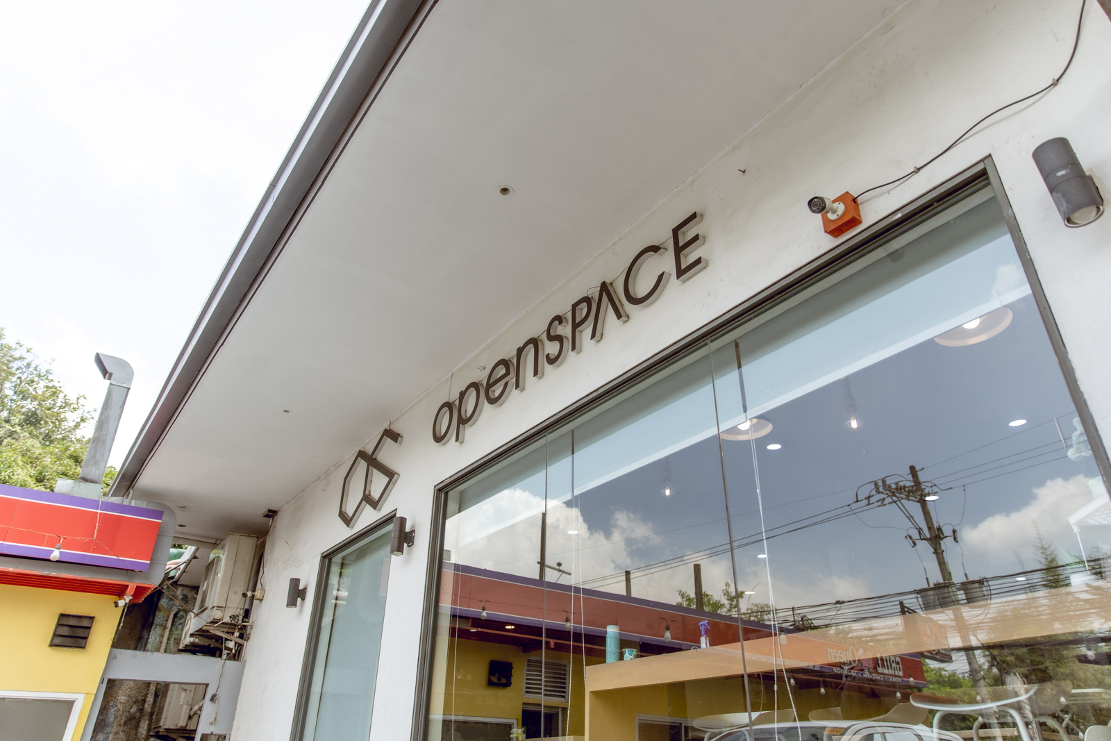 Photograph of a building exterior featuring a large glass window and a sign of Openspace Katipunan, a co-working space located along Esteban Abada St., Quezon City.