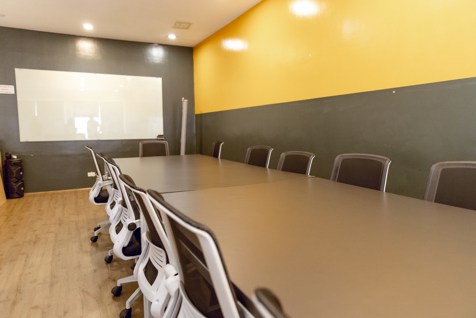 Photograph of a modern conference room for meetings and presentations featuring a long rectangular table surrounded by black and white office chairs on a wooden floor in Openspace Katipunan co-working space along Esteban Abada St.